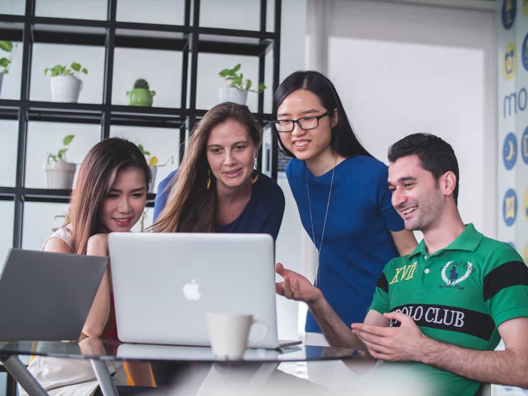 Team members in an office setting, seated in front of laptops, enhancing communication and collaboration through centralized knowledge management software